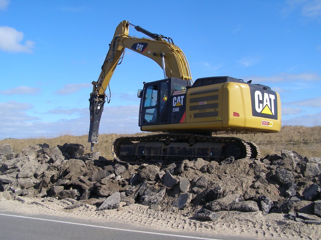 Verschiedene Baumaschinen stehen aufgereiht auf einem Auktionsgelände.